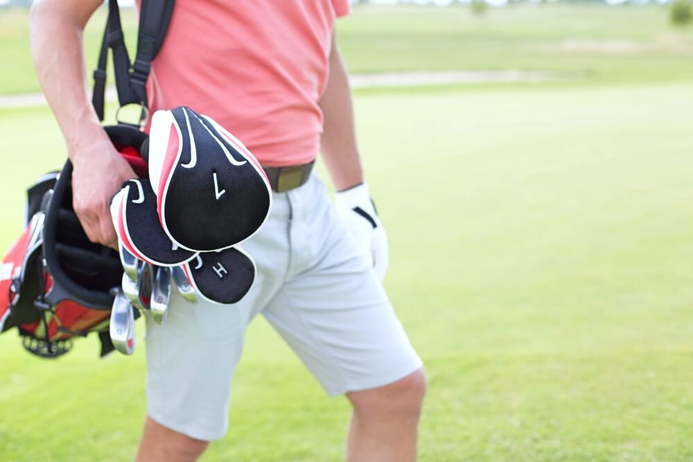 Midsection of Man Carrying Golf Club Bag at Course