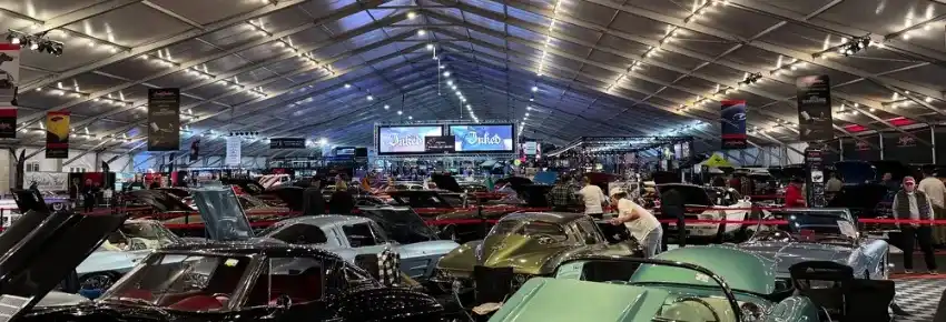 Things-to-Do-in-Scottsdale-Arizona-7 Indoor car show with rows of classic cars under a large, lit tent; attendees walk among the vehicles.